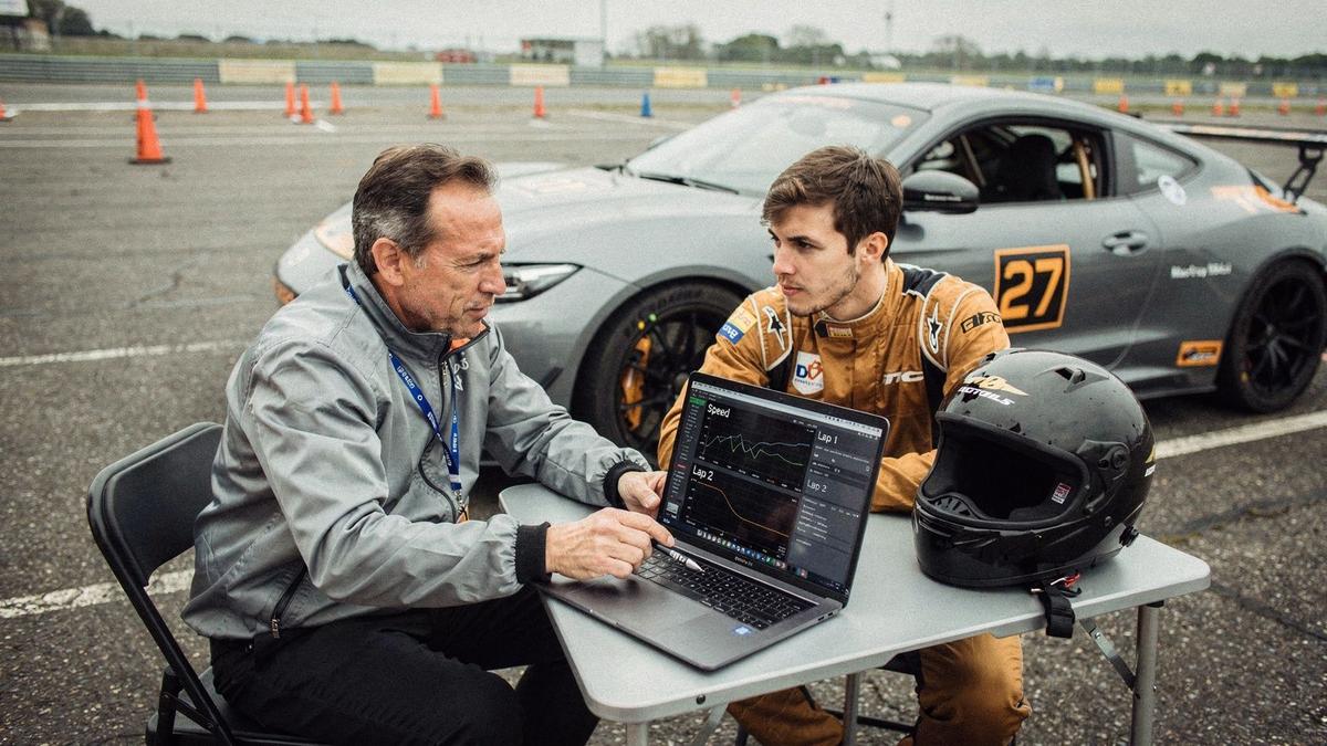 Instructor and driver reviewing logged entry and exit speed traces after a run on a closed handling course